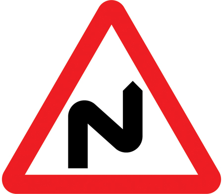 UK double bend warning sign: a red-bordered triangle showing a double bend, first to the right.