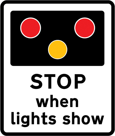UK warning triangle showing light signals at an ungated level crossing ahead.